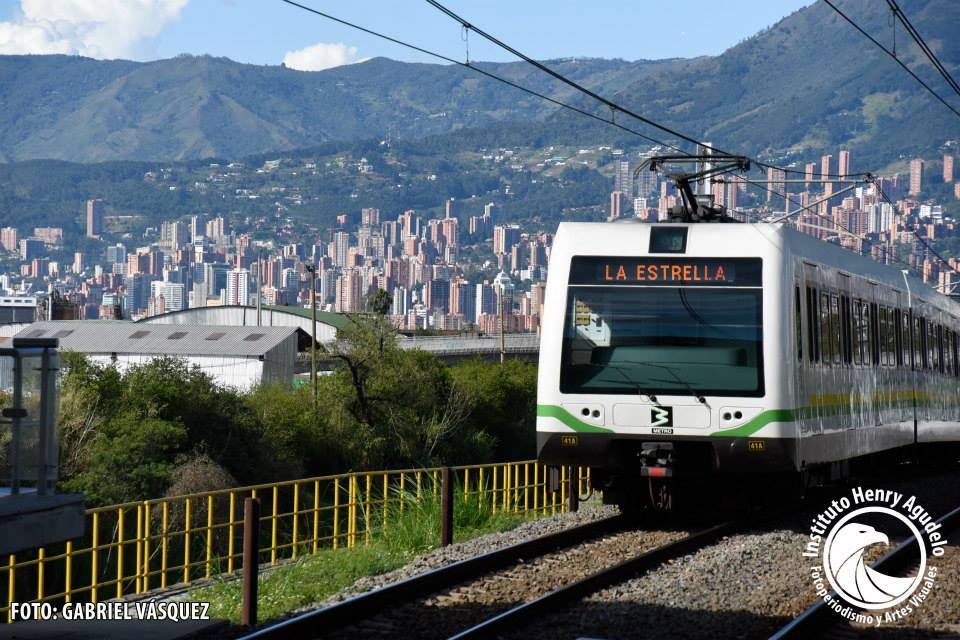 A train is traveling down the tracks in front of a city.