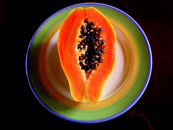 A plate with a cut in half papaya on it.