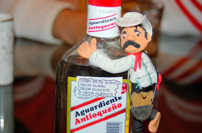 A bottle of alcohol with a toy cowboy on top.