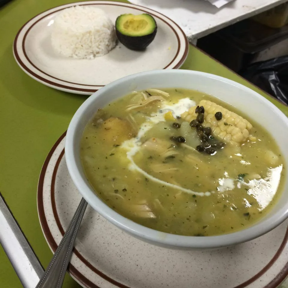 A bowl of soup on the table next to a plate.