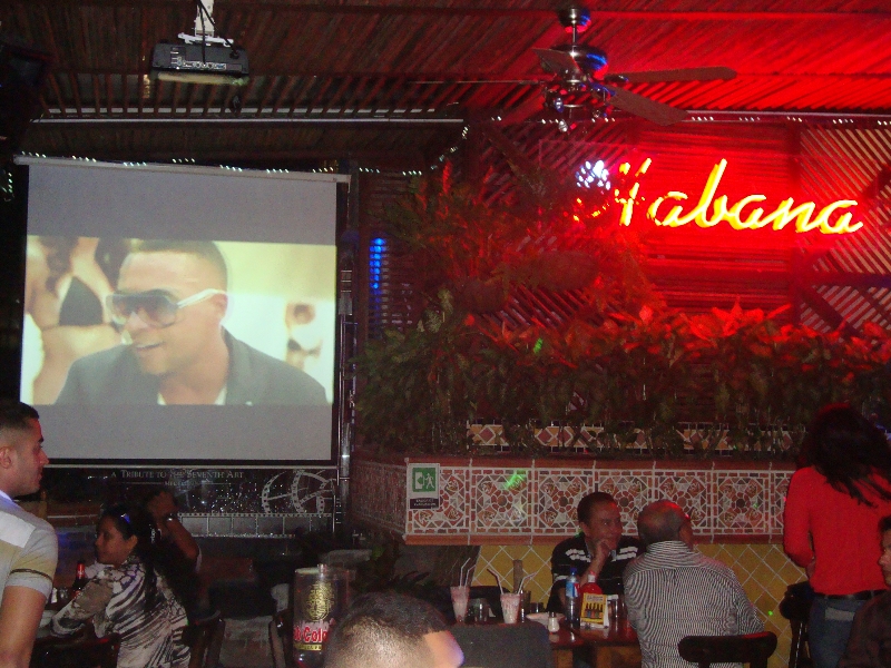 A group of people sitting at tables in front of a screen.