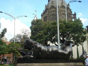 A statue of a man and woman in the middle of a park.