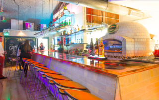 A bar with many bottles of alcohol on the counter.